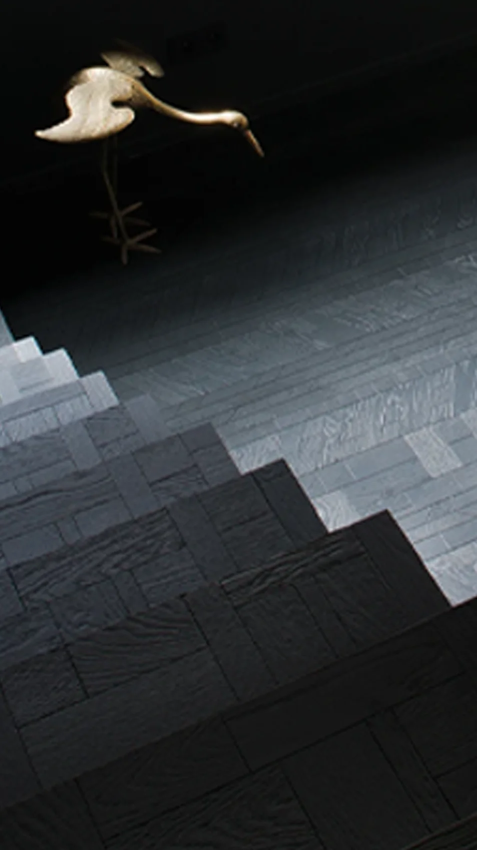 A staircase in black and grey Forêt endgrain oak, a bird sculpture above it